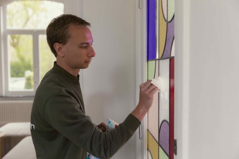 Wouter strijkt over het lood in een glaspaneel in een deur